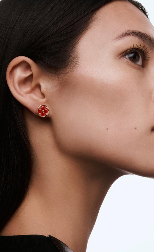 Close-up of a woman wearing red earrings on a plain background