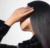 Person with a ring on their finger touching their hair against a white background