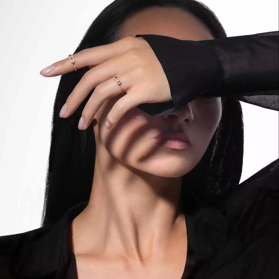 Person wearing a black outfit with a Move Uno Ring on hand that covering their face, on a white background
