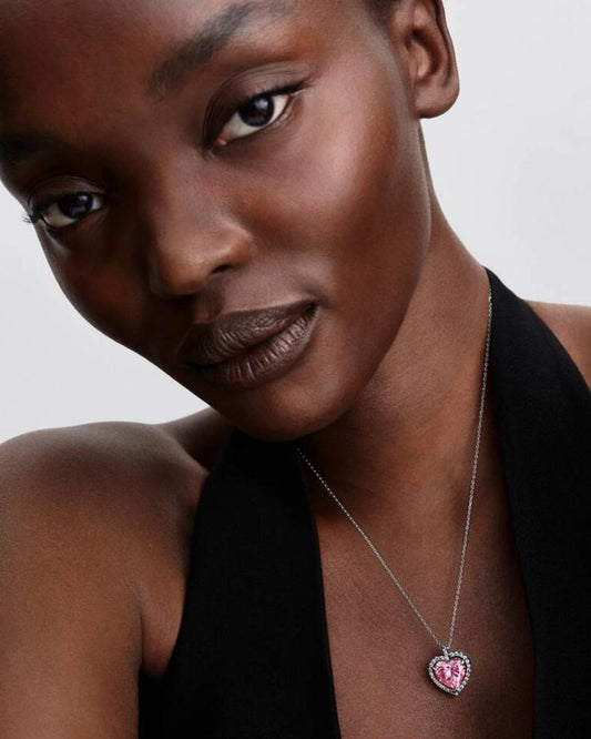 A beautiful model in a black halter top wearing the Rosavie pink heart moissanite necklace, showcasing an elegant high-fashion look.