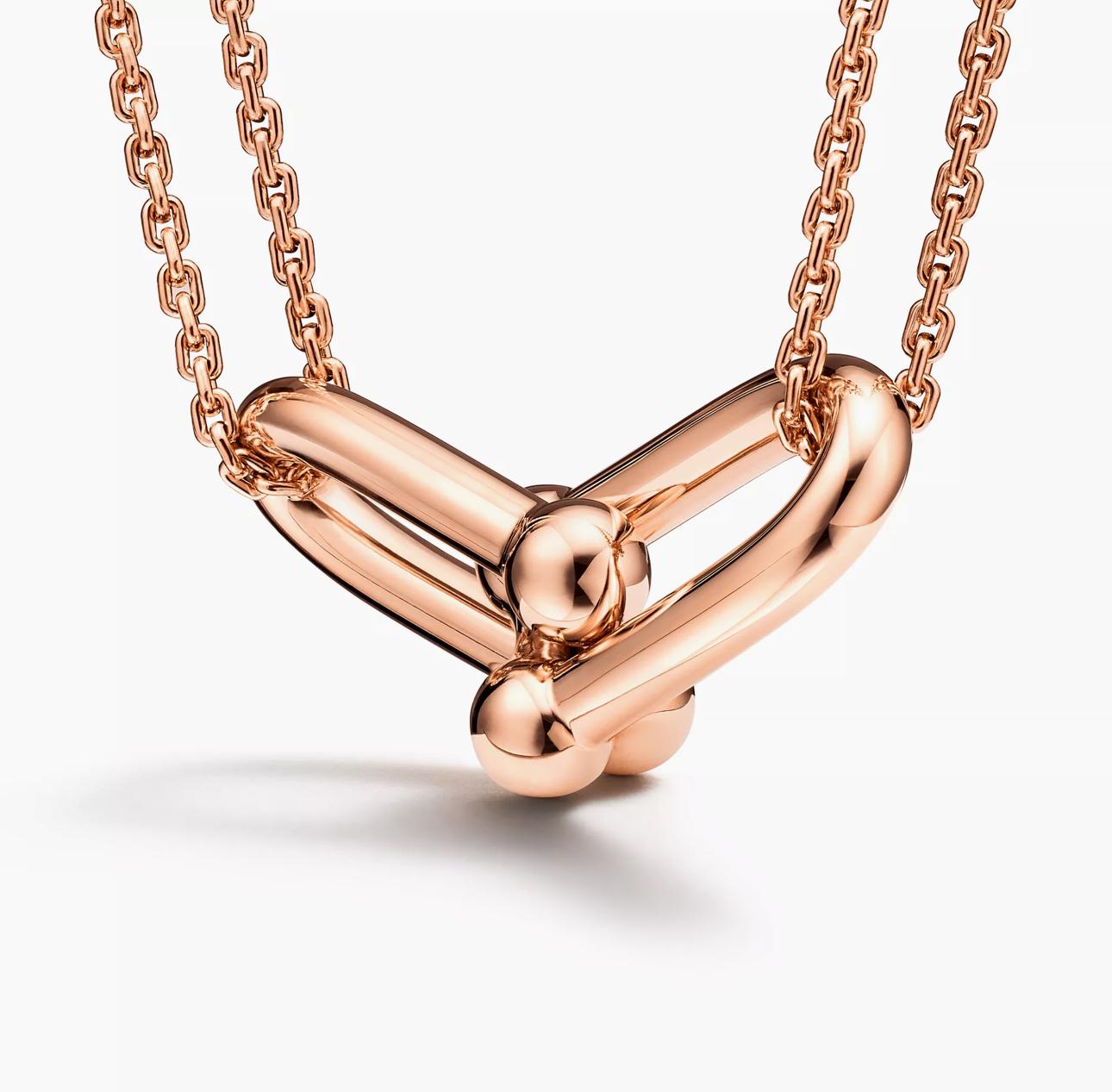 Close-up of a rose gold knot pendant necklace with a polished modern design on a double chain.