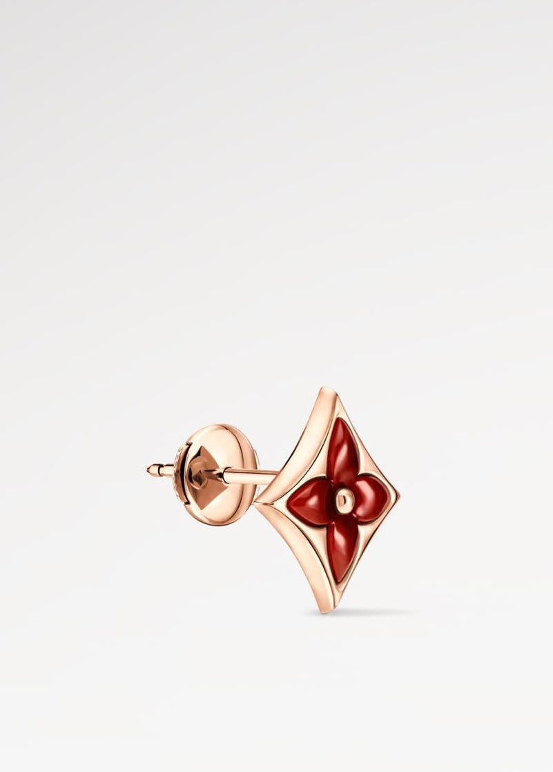 Rose gold earring with red gemstone on a light gray background