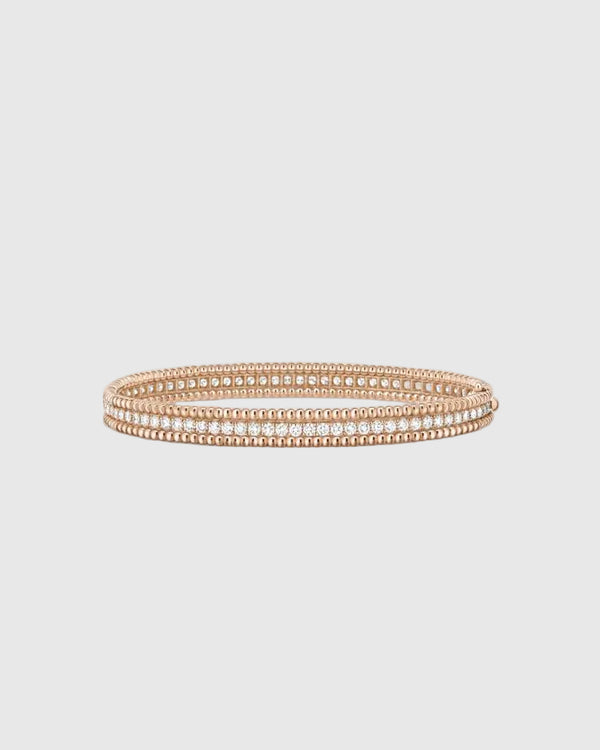 Angled studio view of the Lumina Perlina 18K rose gold-plated solid silver bangle, highlighting the iconic beaded contour flanking a single row of VVS1 moissanite stones.
