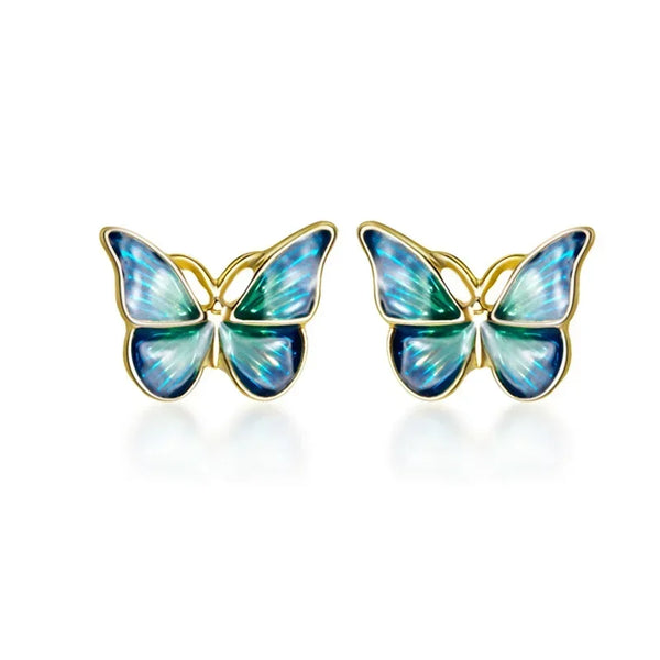 A pair of colorful butterfly stud earrings crafted from real 925 sterling silver, displayed on a beige fabric surface.