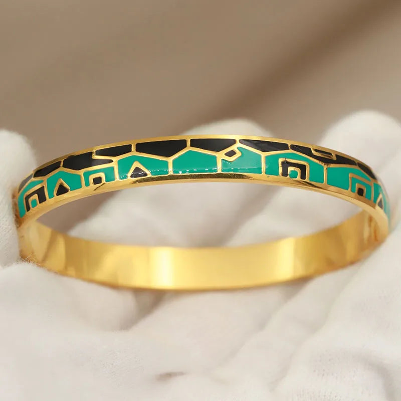 Gold bracelet with green and black pattern on a white surface