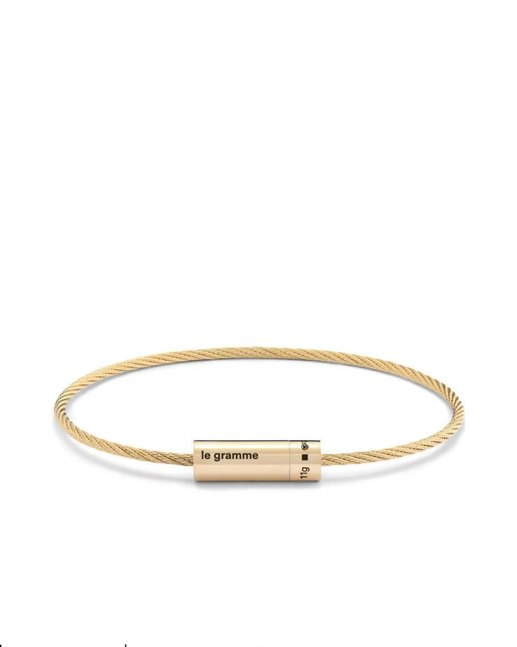 Gold bracelet with cylindrical gold tag on a white background