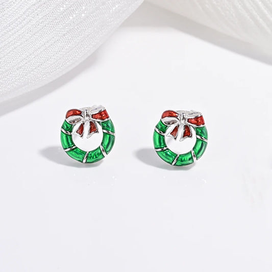A collection of children's jewelry featuring studs in the shapes of cherries, strawberries, and festive trees, with a white and green color scheme.