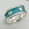 Silver ring with turquoise band featuring heart designs on a white background