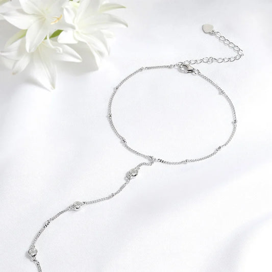 Silver hand chain on a white background with a white flower