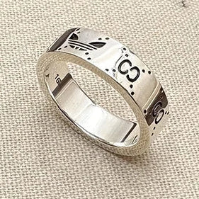 Silver ring with engraved designs on a beige fabric background