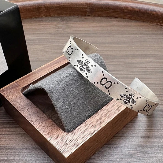 Wooden stand with gray sponge and white ribbon with black bee design on a wooden surface.