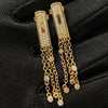 Gold earrings with chain details on a black fabric background