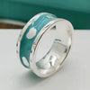 Silver ring with turquoise band featuring white patterns on a white surface.