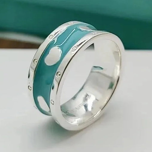 Silver ring with turquoise band featuring white patterns on a white surface.
