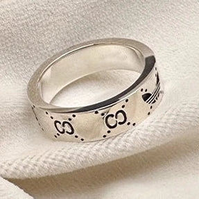 Silver ring with engraved designs on a white fabric background