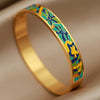 Gold bracelet with colorful enameled design on a beige background