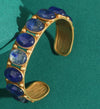 Gold bracelet with blue stones on a green background