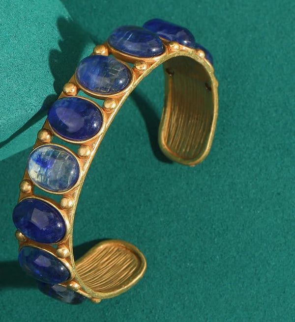 Gold bracelet with blue stones on a green background