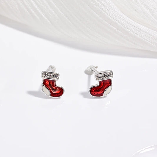 A collection of children's jewelry featuring studs in the shapes of cherries, strawberries, and festive trees, with a white and green color scheme.