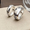 Two silver rings with engraved designs on a textured surface