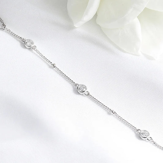 Silver bracelet with small round stones on a white background