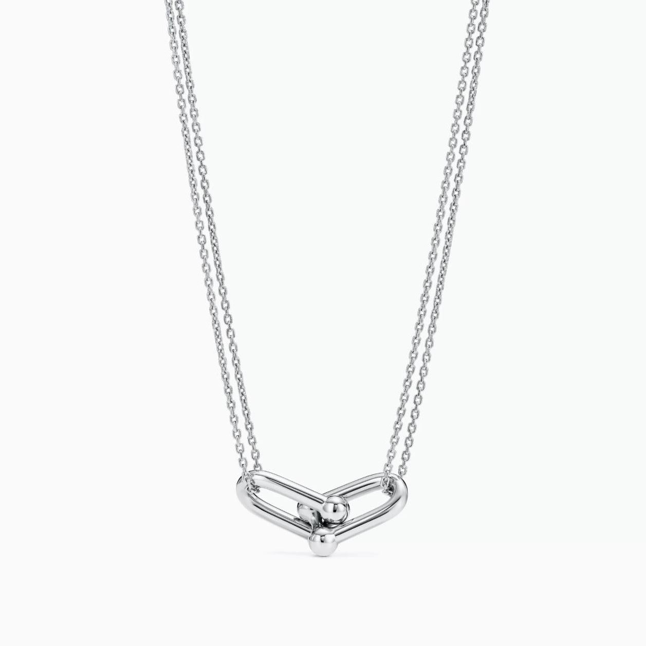 A silver double-chain horseshoe-link necklace featuring a polished modern knot pendant in a minimalist design.