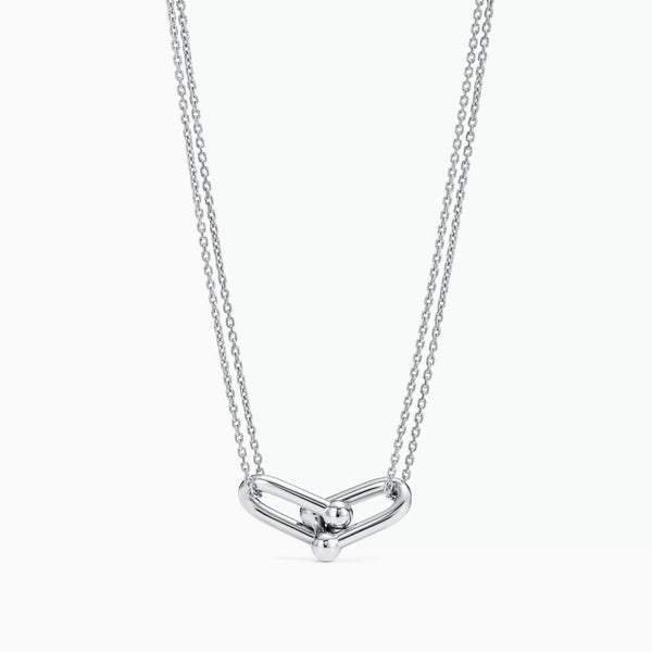 A silver double-chain horseshoe-link necklace featuring a polished modern knot pendant in a minimalist design.