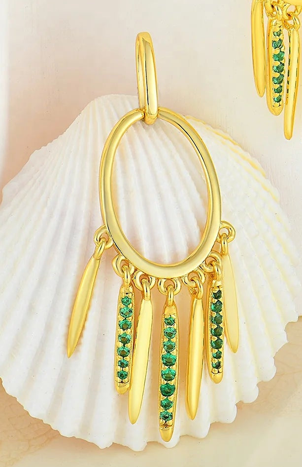 Close-up of a hoop earring with emerald details on a neutral background