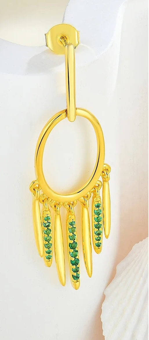 Close-up of a hoop earring with emerald details on a neutral background
