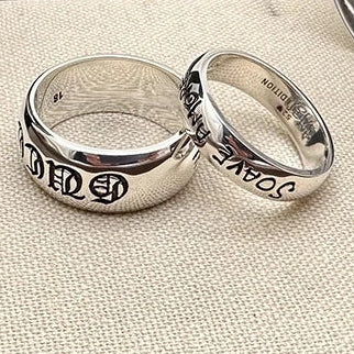 Two silver rings with engraved text on a textured fabric background