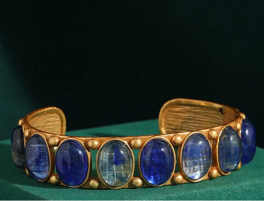 Gold bracelet with blue stones on a green box