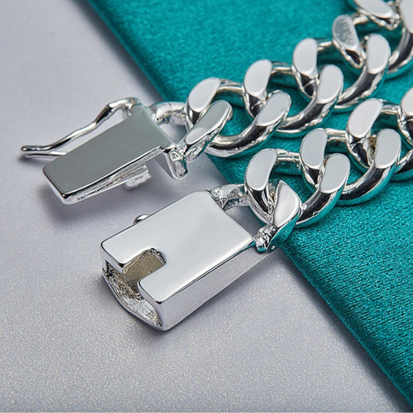 Close-up of silver chain bracelet on teal fabric background.