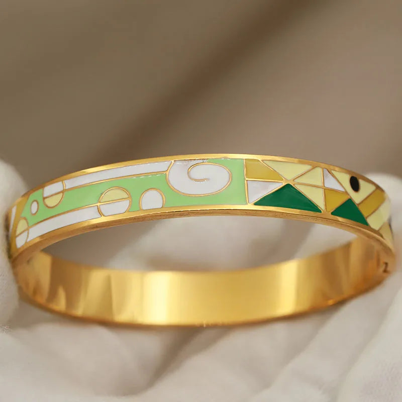 Gold bracelet with green and white pattern on a beige background