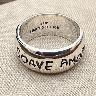 Silver ring with 'COAVE AMOR' engraved on a textured beige background