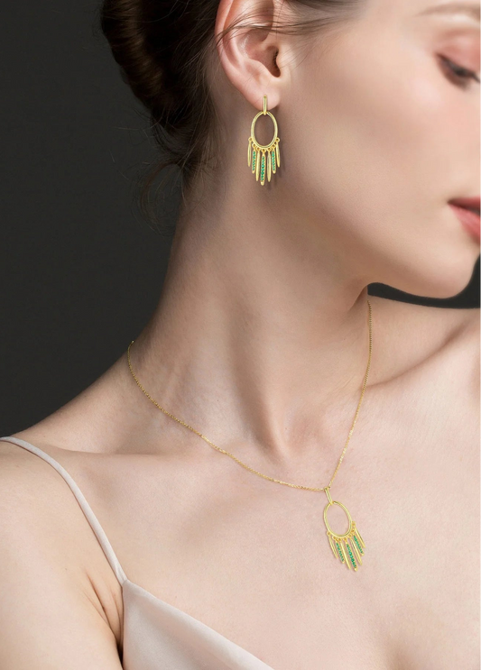 Woman wearing a gold necklace and earrings against a dark background