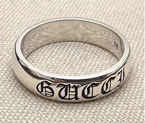 Silver Gucci ring on a textured beige background