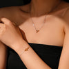 Necklace and bracelet with heart-shaped pendants on a person against a neutral background