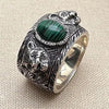 Silver ring with green stone and bear design on a beige fabric background