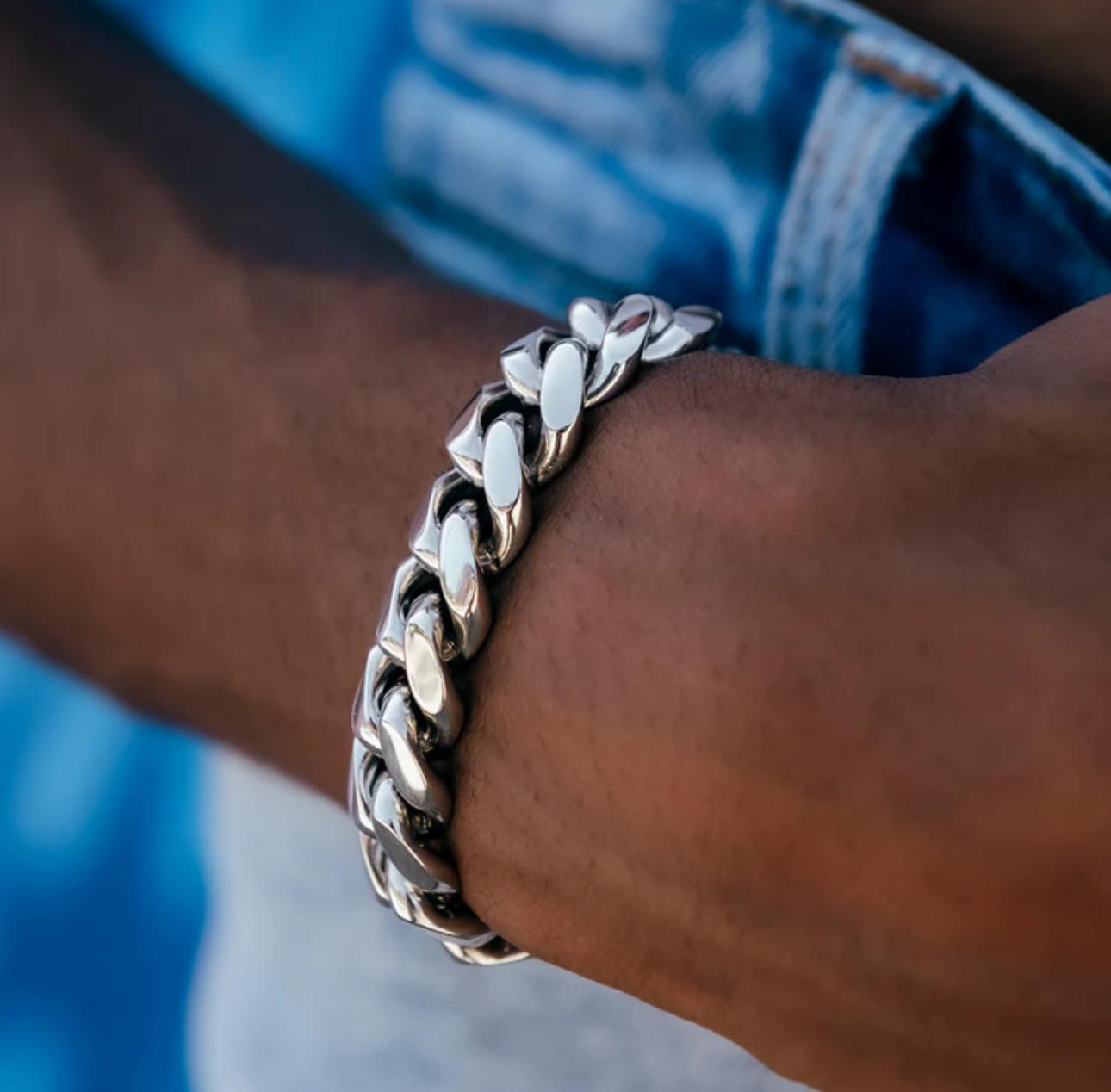 Close-up of a person's wrist wearing a silver chain bracelet with a blurred background.