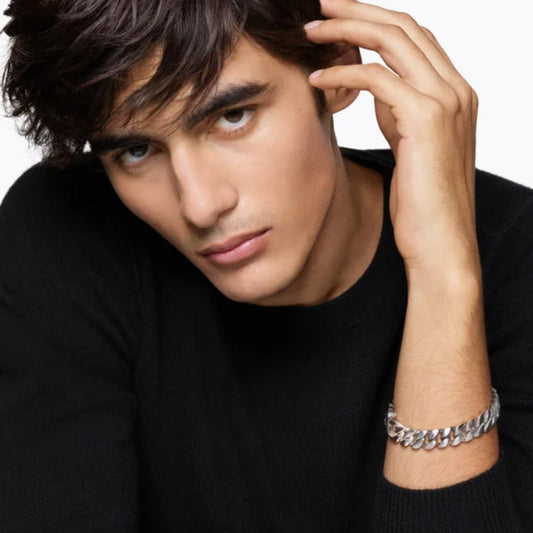 Man wearing a black sweater with a silver Curb Chain Bracelet on a plain background
