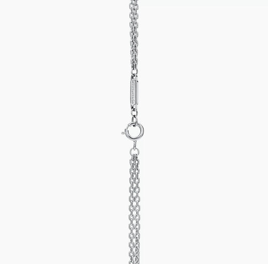 Close-up of a silver necklace clasp and chain detail, showing a polished ring and bar connection.