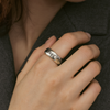 Silver ring with engraved text on a person's finger against a dark background