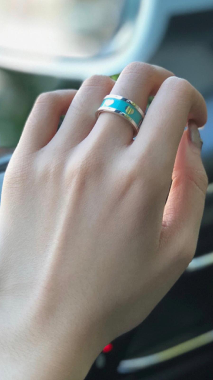 Close-up of a hand wearing a silver ring with Tiffany Blue® enamel finishring with a blurred background