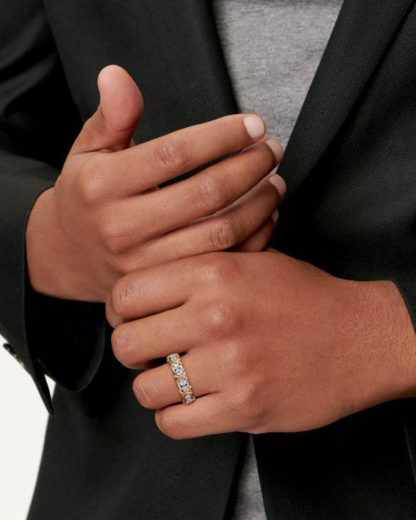 A close-up shot of a model wearing the Aurelia XVI two-tone solid 925 silver and 18K gold ring, featuring 1.14ct round brilliant moissanite stones and interlaced cross-stitch X motifs.