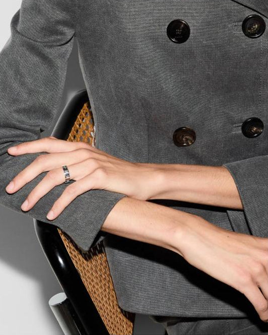 a person wearing a VELTORI BAND RING WITH BEES AND GG.