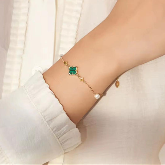 Bracelet with a green clover charm on a wrist against a white background