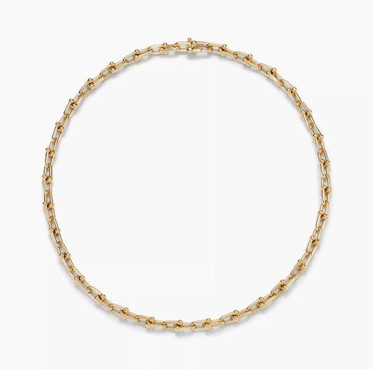 Gold chain Horsebit link design necklace on a white background