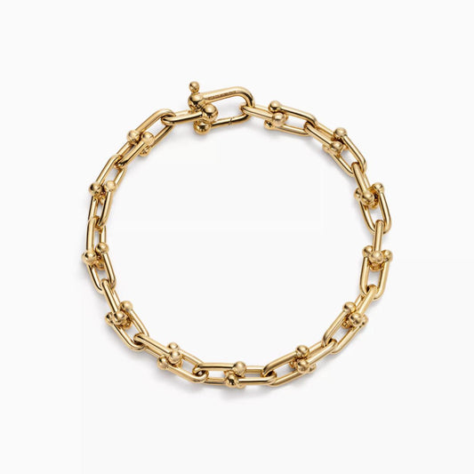 Gold horsebit link chain bracelet on a white background