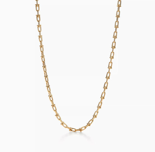 Gold chain Horsebit link design necklace on a white background