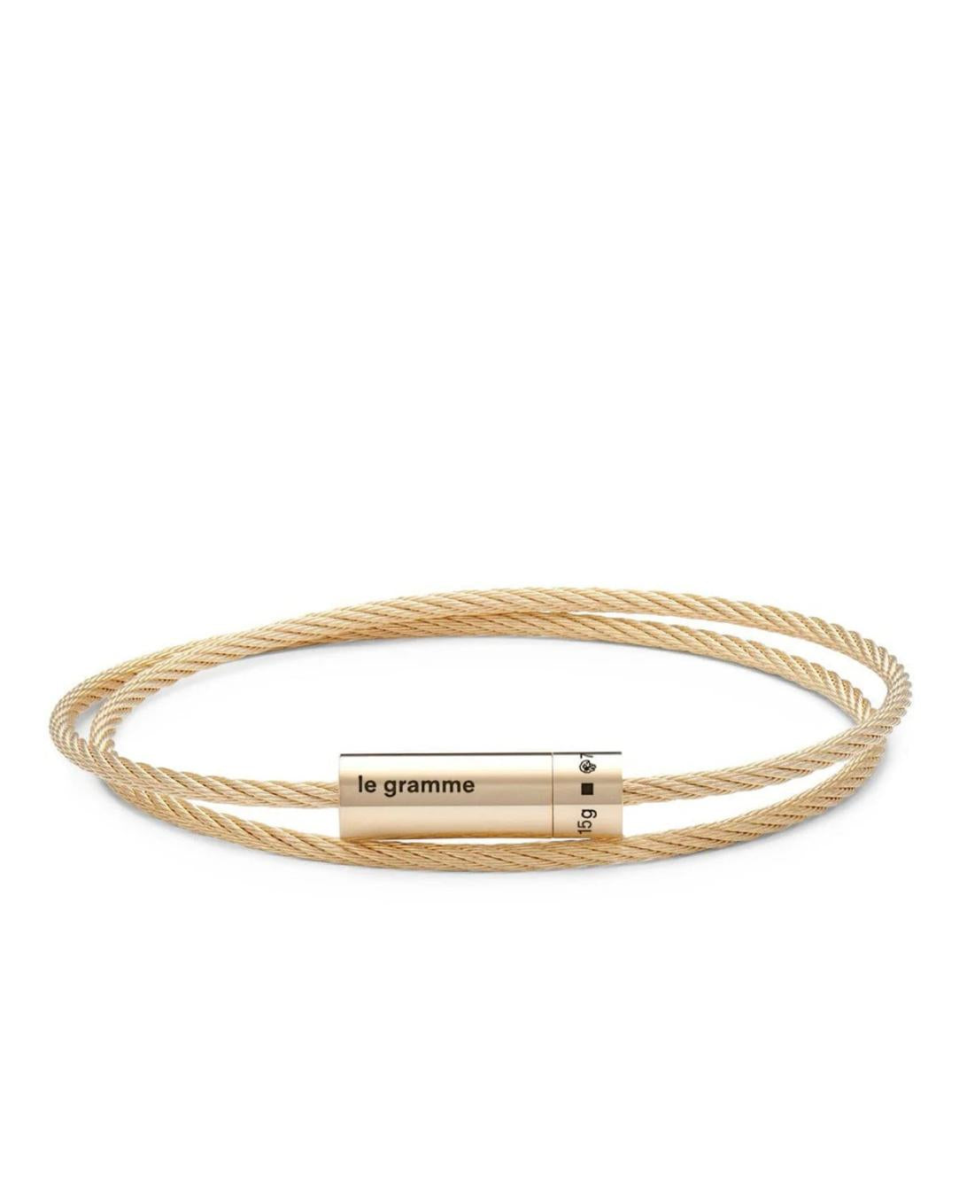Gold cable bracelet with a cylindrical tag on a white background